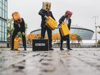 Ocean Rebellion activists dressed as Oilheads spew an oil like substance across the ground on the south bank of the river Clyde across from...