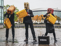 Ocean Rebellion activists dressed as Oilheads spew an oil like substance across the ground on the south bank of the river Clyde across from...