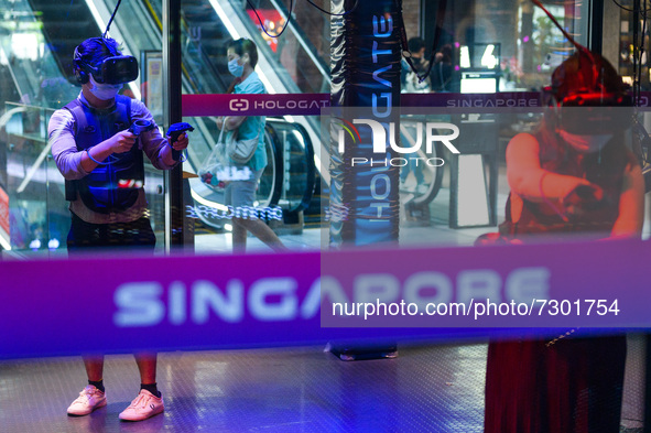 People in protective masks play a virtual reality game in a shopping mall in Singapore on Saturday, 30 October, 2021. Only fully vacinated a...