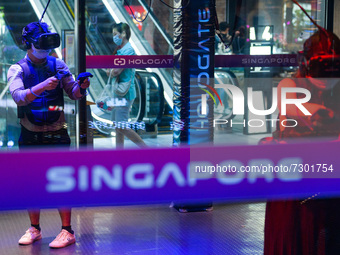 People in protective masks play a virtual reality game in a shopping mall in Singapore on Saturday, 30 October, 2021. Only fully vacinated a...