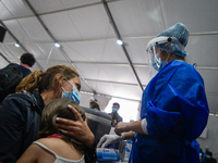 A mother covers the eyes of her daughter as she receives its first dose of SINOVAC COVID-19 vaccine as the Colombian government begins to va...