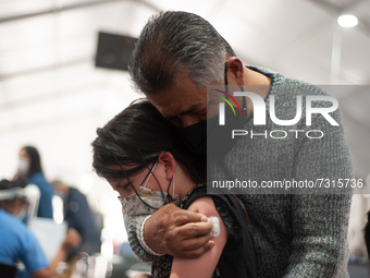 A tutor hugs his child after getting the first dose of the COVID-19 Vaccine as the Colombian government begins to vaccinate children between...