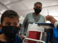A tutor supervises how his child is applied with the first dose of SINOVAC's COVID-19 vaccine as the Colombian government begins to vaccinat...