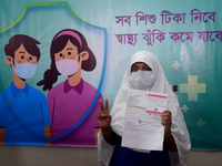 Bangladeshi school student shows the V sign after receiving a first dose of the Pfizer COVID-19 vaccine at the Ideal School and College cent...