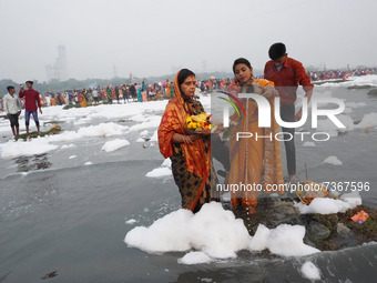 Hindu devotees offer prayers as they stand amidst the polluted waters of the river Yamuna covered with a layer of foam, on the occasion of C...
