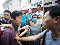 A government official being stopped by the angry residents while he tries to enter the hotel for the press conference.   - Hundreds of resid...