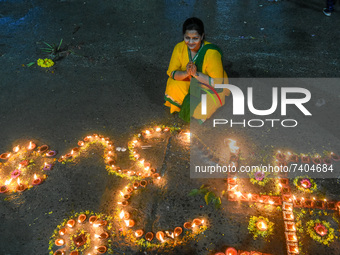A lady prays in front of lighted earthen oil lamps at a river Ghat , on the occasion of Dev Deepavali in Kolkata , India , on 18 November 20...