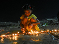 A little child is seen lightning earthen lamps on the occasion of Dev Deepavali ,at a riverside in Kolkata , India , on 18 November 2021 . D...