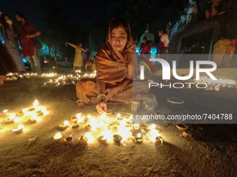 A lady prays in front of lighted earthen oil lamps at a river Ghat , on the occasion of Dev Deepavali in Kolkata , India , on 18 November 20...