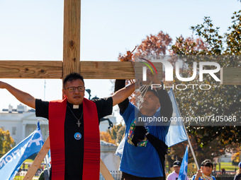 A protester ties the wrists of immigration activist Jose Landaverde to a wooden cross during a direct action by the National TPS Alliance at...