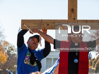 A protester ties the wrists of immigration activist Jose Landaverde to a wooden cross during a direct action by the National TPS Alliance at...