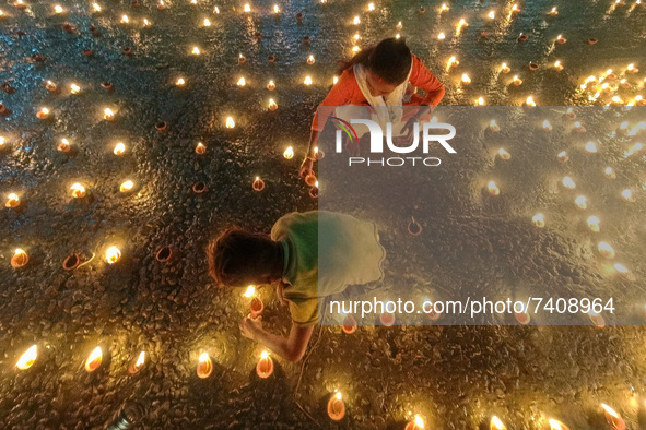 A mother and son is seen lighting oil lamps on the occasion of Dev Deepavali in Kolkata , India , on 19 November 2021 . Dev Deepavali is a H...