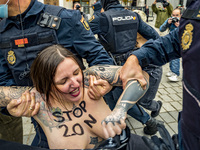 (EDITOR'S NOTE: Image contains nudity) Femen activist with a 20N painted in her breast, is arrested by the police during a fascist rally for...