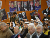 Palestinians sit near posters depicting the crossed-out faces of Britain's current Prime Minister Boris Johnson, Home Secretary Priti Patel,...