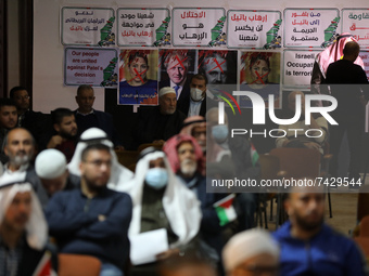 Palestinians sit near posters depicting the crossed-out faces of Britain's current Prime Minister Boris Johnson, Home Secretary Priti Patel,...