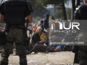 A young migrant mother and her chiled looks behind the barb wire, while he and thousands of other migrants are being held in the zone betwee...