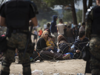 A young migrant mother and her chiled looks behind the barb wire, while he and thousands of other migrants are being held in the zone betwee...