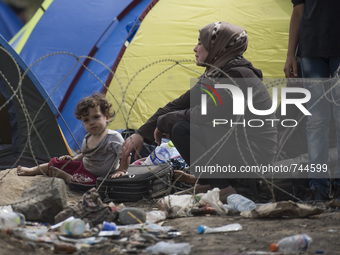 A migrant woman and her child wait on the Macedonian-Greek border where she and other migrants are being held, since Macedonia declared emer...