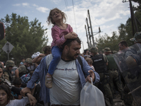 A migrant child and her father pass through the cordon of policeman and enter Macedonia, after they and other migrants were waiting on the M...