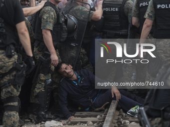 A migrant man faints after waiting on the Macedonian-Greek border where migrants are being held, since Macedonia declared emergency at its b...