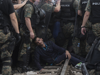 A migrant man faints after waiting on the Macedonian-Greek border where migrants are being held, since Macedonia declared emergency at its b...
