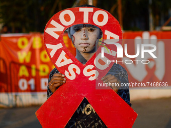 A girl is seen with painted messages on her face holding a placard to raise awareness towards AIDS , during World AIDS day observation in Ko...
