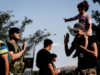 A Syrian girl greets a Macedonian police officer as she crosses the border with her father from the Greek side. Gevgelija, August 23, 2015....