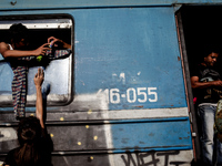 A woman gives candy to young refugees just before they leave for the Macedonian-Serbian border by train. Gevgelija on August 23, 2015. (Phot...