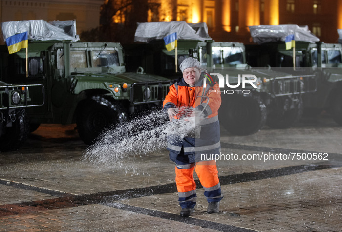 A communal worker sprinkles salt to a prevent slippery ground, before an official ceremony to hand over of 13 'High Mobility Multipurpose Wh...