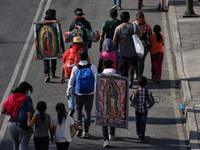 A faithful  holds an image of Virgin Of Guadalupe in their back while walks along Ignacio Zaragoza Avenue to arrive the Basilica of Guadalup...