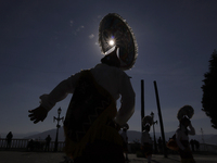 Backlighting of dancers and pilgrims while performing the Dance of the Quetzals in the square of the Monumental Virgin of Guadalupe located...