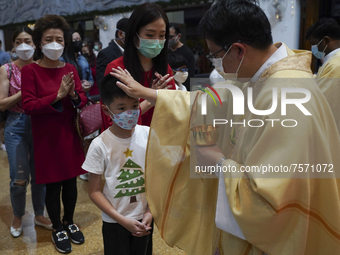 Thai Catholic priests offer the communion wafer to church goers during Christmas Eve at a church in Bangkok, Thailand, 24 December 2021. (