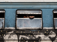 A migrant man looks through a window onboard a train for Serbia at the new transit center for migrants at the border line between Greece and...