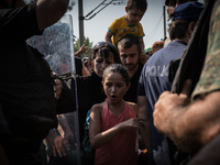 Migrants wait for the Macedonian police to allow them to cross into Macedonia at the border between Greece and Macedonia near the town of Ge...