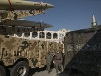 Two Iranian Islamic Revolutionary Guard Corps (IRGC) military personnel walk past Iranian solid-propelled road-mobile single-stage missile,...