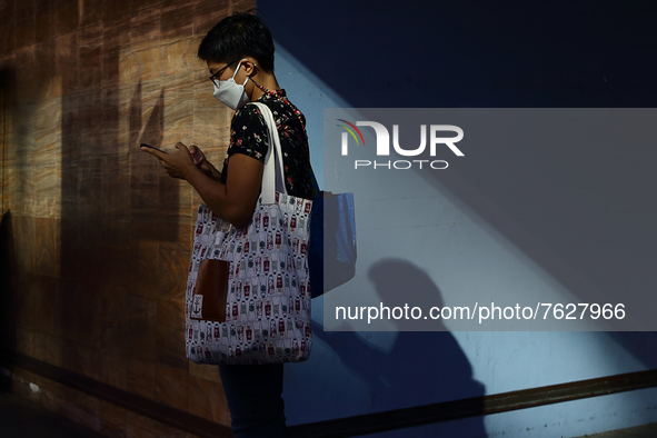 A woman wearing protective mask uses her mobile phone while waiting for a bus on January 13, 2022 in Singapore. 
 