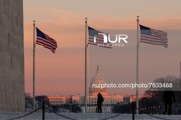 People watch a beautiful sunset over the Capitol from the Washington Monument after an unexpected snowstorm dumped roughly 8 inches on Washi...