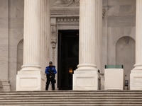 A Capitol Police officer stands guard with an assault rifle against faith Leaders and hunger strikers sitting on the steps of the Senate cha...