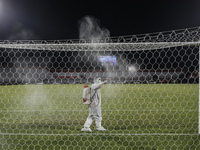 Workers sprays disinfectant to a goal net and bar during half time of FIFA friendly match between Indonesia against Timor Leste amid Covid-1...