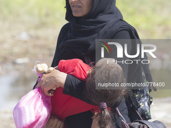 A woman carries a child in Gewgelika, Macedonia, on September 11, 2015. Around 7,600 migrants entered Macedonia in just 12 hours overnight -...