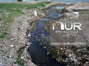 An indian man walks side of  heaps of waste in a waterway leading into a the River Ganges in Allahabad on September 21, 2015. The Ganges is...