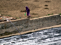 An indian woman walks on a side wall of  a polluted  tributary flowing into a the River Ganges in Allahabad on September 21, 2015. The Gange...