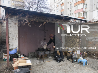 A woman is preparing a meal on fire next to apartments blocks in the recaptured by the Ukrainian army Bucha city near Kyiv, Ukraine, 04 Apri...