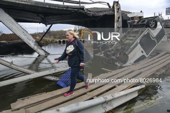 Woman cross the Irpin river near a destroyed bridge outside the recaptured city of Irpin, Ukraine, 06 April 2022 
