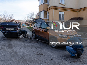 BUCHA, UKRAINE - APRIL 7, 2022 - Men examine destroyed cars after the liberation of the city from Russian invaders, Bucha, Kyiv Region, nort...