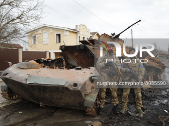Two Ukrainian soldiers are seen in front of a destroyed Russian tank in Bucha, after the Ukrainian forces recaptured the town, amid the Russ...