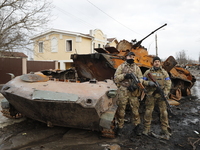 Two Ukrainian soldiers are seen in front of a destroyed Russian tank in Bucha, after the Ukrainian forces recaptured the town, amid the Russ...