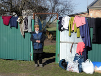 KYIV REGION, UKRAINE - APRIL 07, 2022 - A local woman stands by the fence hung with clothes as part of the humanitarian aid for the people i...