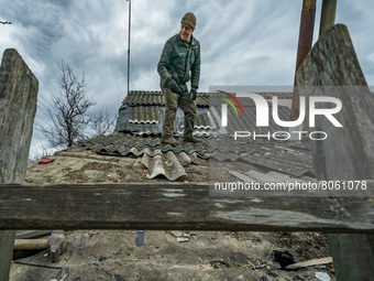 A man repairs the roof of his house after being shelled by russian army during the combats between the ukrainian and russian armies for the...