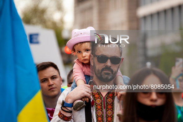 A young girl gets a ride on her father's shoulders as they march to the residence of the Russian ambassador during a protest against the war...